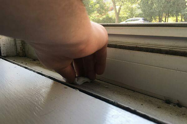 Closeup of hand using dust wipe on interior window sill
