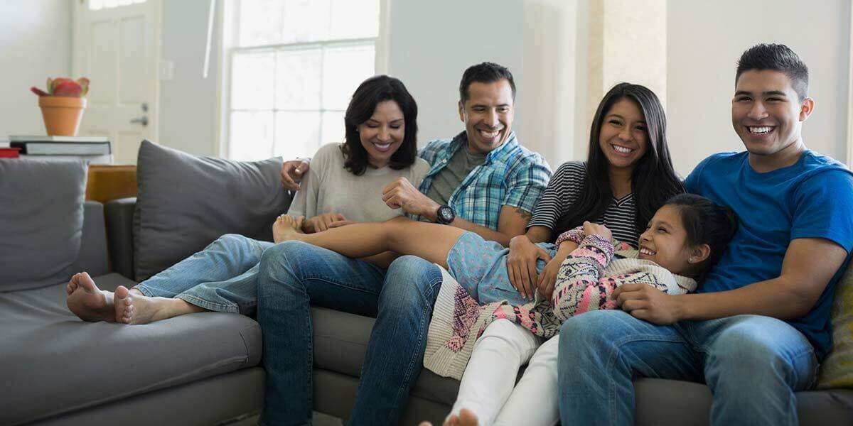 Family of five sitting on couch together and smiling